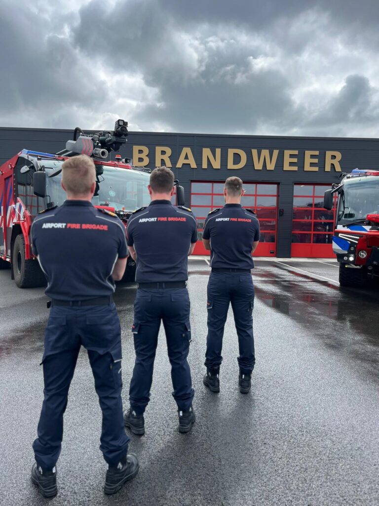 Een foto van 3 brandweermannen voor de kazerne van Brandweer Lelystad